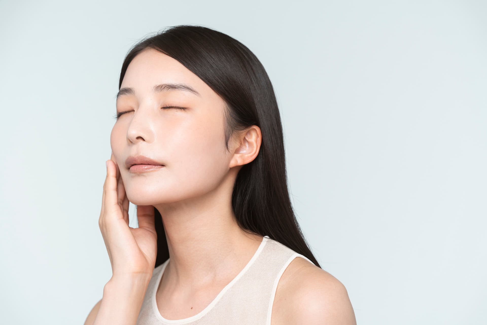 冷灰藍背景前,女性閉眼以手掌輕貼臉頰