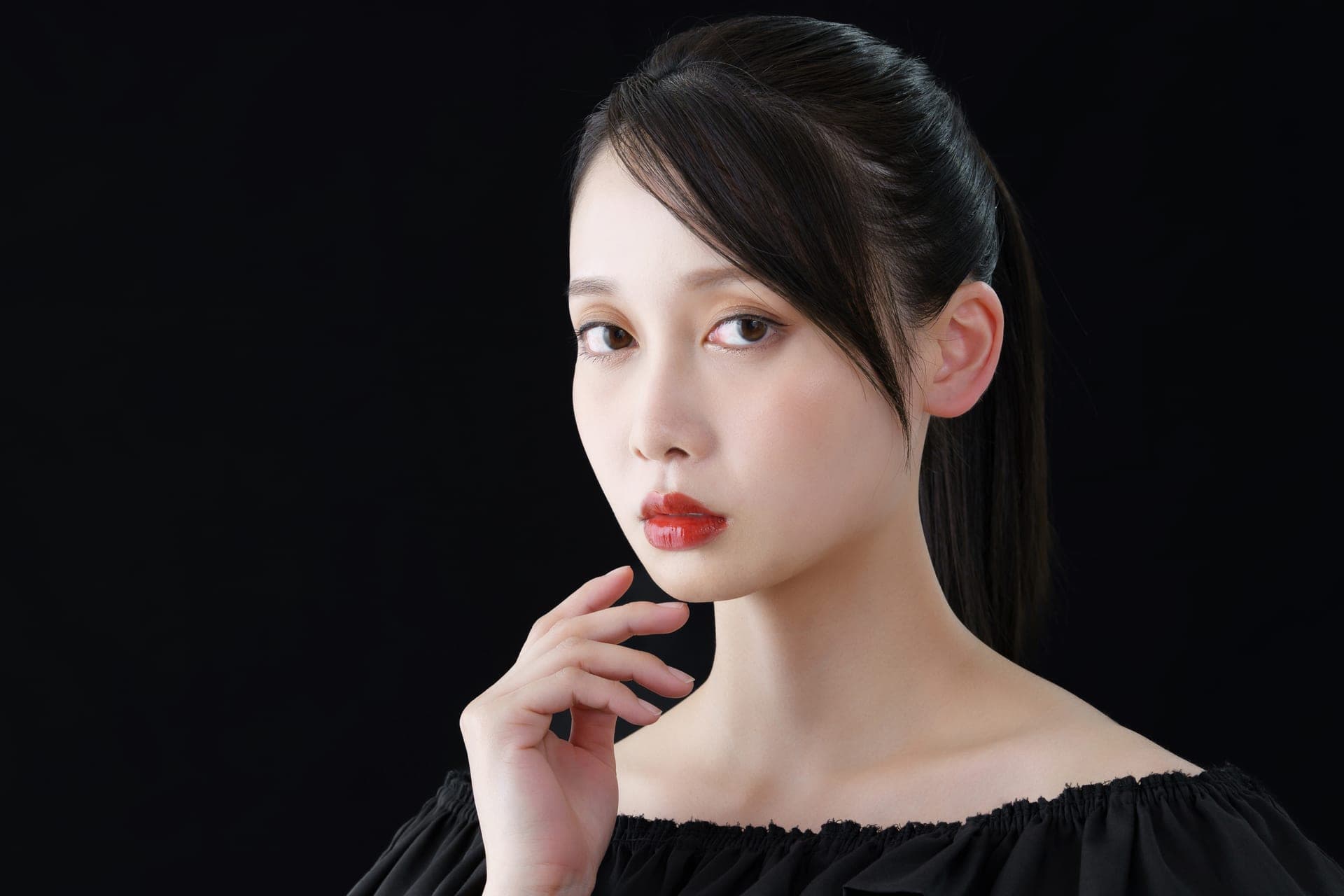側光下若有所思的東方女性,指尖輕抵下顎,象徵外泌體保養需要跟著肌膚的時間慢慢感受