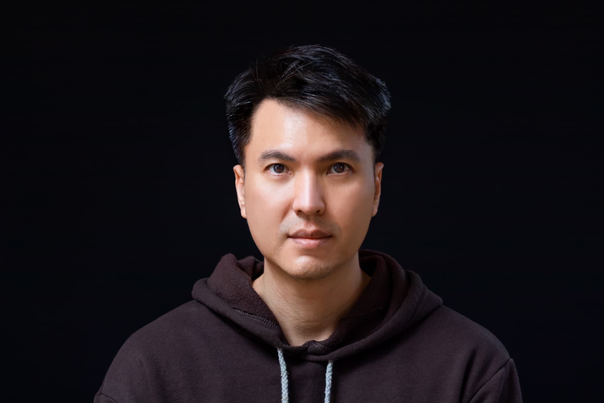 暗色背景中一位穿深色帽 T 的東方男性肖像,膚況乾淨、神情沉穩,象徵男性的日常肌膚養護
